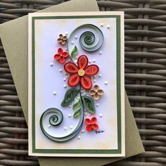 a handmade card with flowers and swirls on the front, sitting on top of a wicker basket