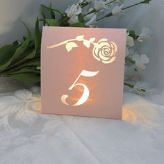 a card with the number five on it and some flowers in front of it that is lit up