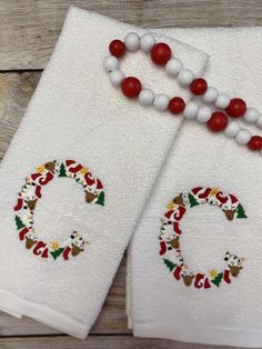 two white towels with christmas decorations on them and beaded necklaces next to each other