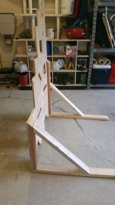 a wooden structure sitting on top of a floor next to shelves filled with clutter