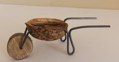 a small wooden object with metal handles on a white tablecloth covered surface, in the shape of a wheelbarrow