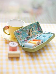 a cup and saucer on a table with sewing supplies