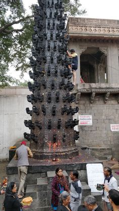 people are gathered around a large sculpture made out of wine bottles and other items in front of a building