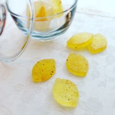 several pieces of potato chips on a white tablecloth next to a glass bowl full of potatoes