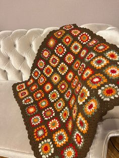 a crocheted blanket sitting on top of a white couch next to a pillow