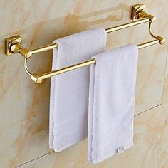 two white towels hanging on a gold towel rack