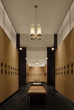 an empty locker room with benches and lights on the wall, along with several rows of wooden lockers