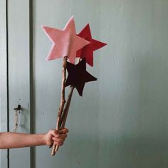 a hand holding a branch with red and black stars on it