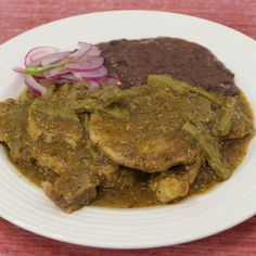 a white plate topped with meat covered in gravy