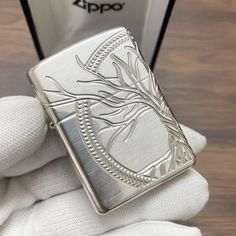 a person is holding a zippo lighter in their left hand and the lighter has a tree design on it