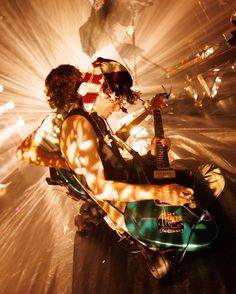 a man sitting on top of a chair next to a woman holding an electric guitar