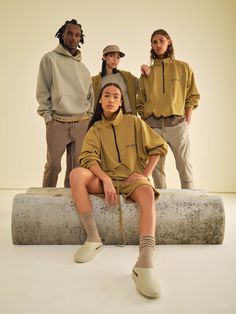 four people are posing for a photo while sitting on a stone slab in front of a white background