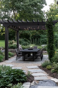 an outdoor dining table and chairs under a pergolated arbor with lights on it