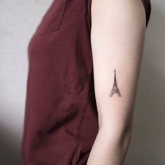 a woman with a small tattoo on her left arm and the eiffel tower behind her