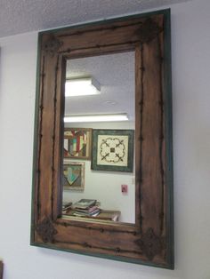 a mirror is hanging on the wall above a shelf with books and other items in it