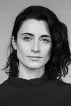 a black and white photo of a woman wearing a turtle neck shirt with her hair in the wind