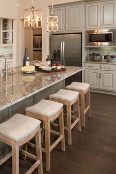 a kitchen with marble counter tops and stools next to an island in the middle