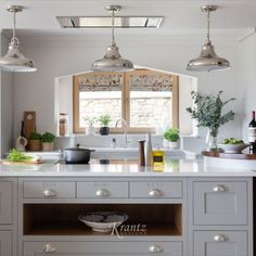 a kitchen with white cabinets and stainless steel lights hanging from the ceiling over the island