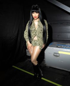 a woman with long black hair standing in front of a suitcase and posing for the camera