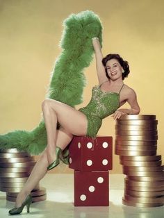 a woman in a green dress sitting on top of stacks of dice