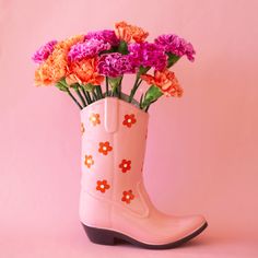 On a pink background is a pink cowboy boot shaped vase with a red and white daisy print on it. Flowers pictured not included with purchase. Disco Cowboy Home Decor, Cowboy Boot Flower Vase, Ceramic Cowboy Boot, Retro Western Aesthetic, Gifting Flowers, Cowboy Boot Vase, Pink Cowboy Boot, Cowboy Home Decor, Pink Vases