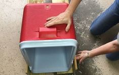 a person is placing a red and blue cooler on top of a pallet in the floor