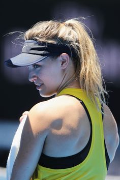 a female tennis player is holding her racket in one hand and wearing a visor on the other