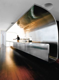 a person standing at a counter in a room with wood floors and white walls on the wall