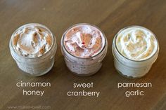 three jars filled with different types of whipped creams on top of a wooden table