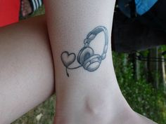 a woman's foot with headphones on it and a tattoo design on the ankle