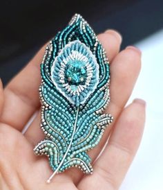 a hand holding a beaded brooch in it's palm