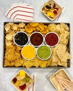 a tray filled with chips, dips and condiments on top of a table