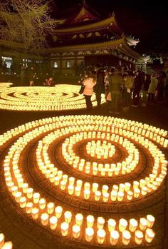 many lit candles are arranged in the shape of a spiral around a building at night