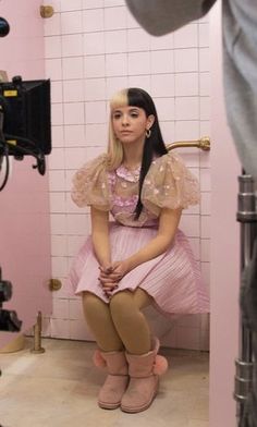 a woman sitting on the floor in front of a mirror with her legs crossed and wearing pink boots