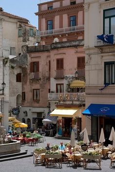 an old building with several tables and chairs in front of it, next to the street