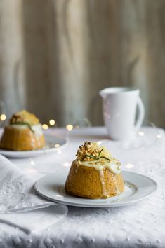 two desserts are sitting on a white tablecloth with silverware and cups in the background