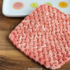 a crocheted dishcloth sitting on top of a wooden table next to a plate