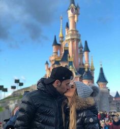 a man and woman kissing in front of a castle