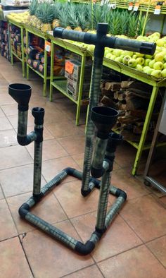 two black pipes are on the ground in front of some fruit and vegetable stand with pineapples