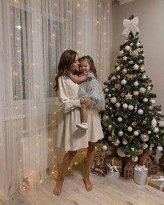 two girls standing in front of a christmas tree