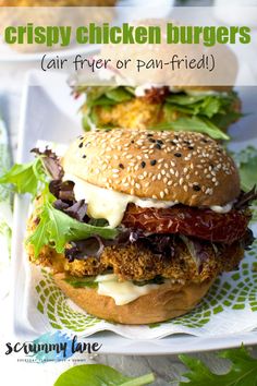 two burgers with lettuce, tomato and other toppings on a plate