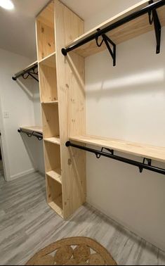 an empty walk in closet with wooden shelves and black metal brackets on the wall next to it