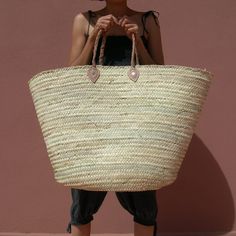 a woman is holding a large woven bag