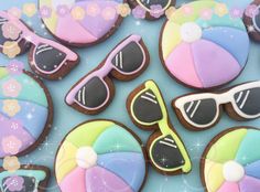 decorated cookies in the shape of beach balls, sunglasses and umbrellas are arranged on a blue surface