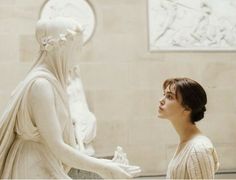 a woman standing next to a white statue