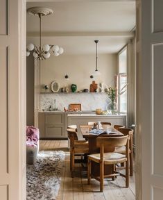 an open door leading to a dining room and kitchen area with wooden table and chairs