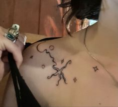 a woman with a tattoo on her chest is looking down at the camera and holding an object in her hand