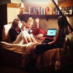 three children are sitting on a bed with their laptops in front of them,