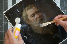 a man with a beard is painting a portrait