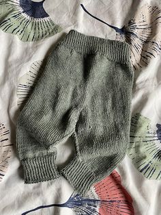 a knitted baby's pants laying on top of a bed